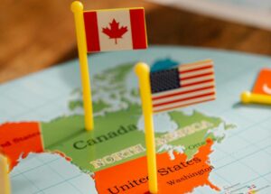 Close-up of miniature Canada and USA flags on a world map depicting North America, symbolizing travel and education.